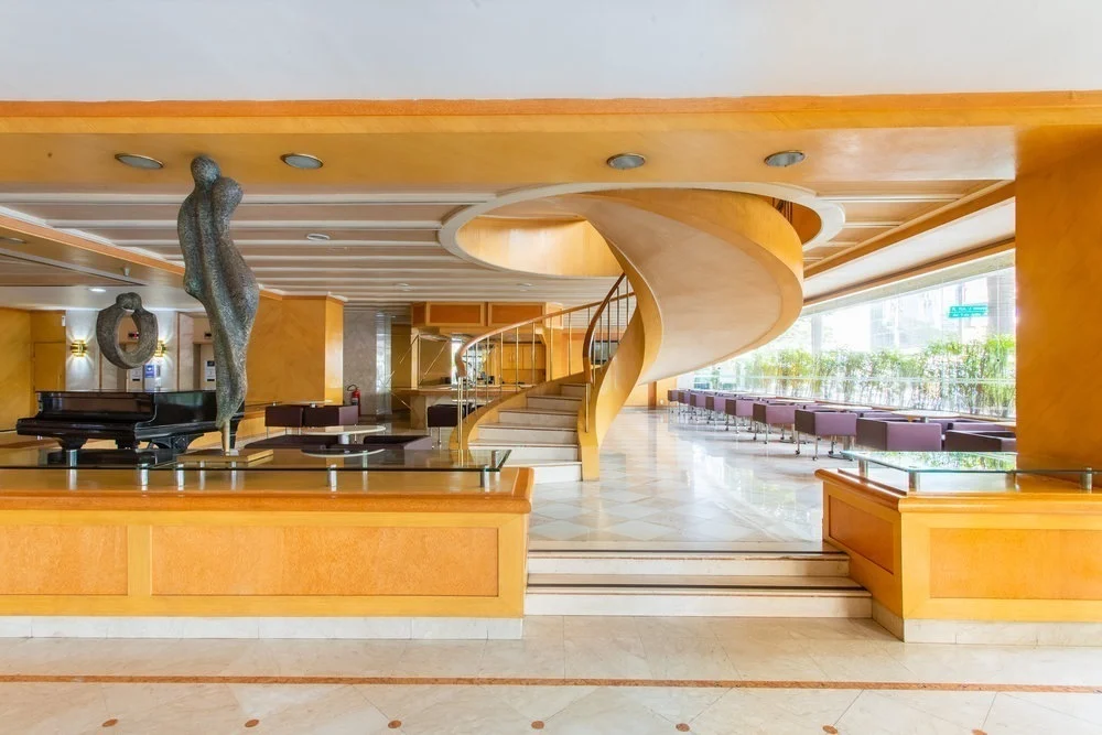 Recepção do hotel com escada em espiral e piano