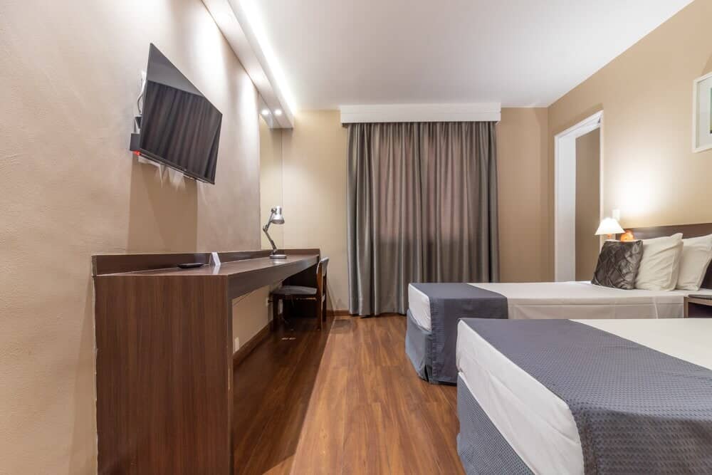Suíte com duas camas, TV e mesa de trabalho